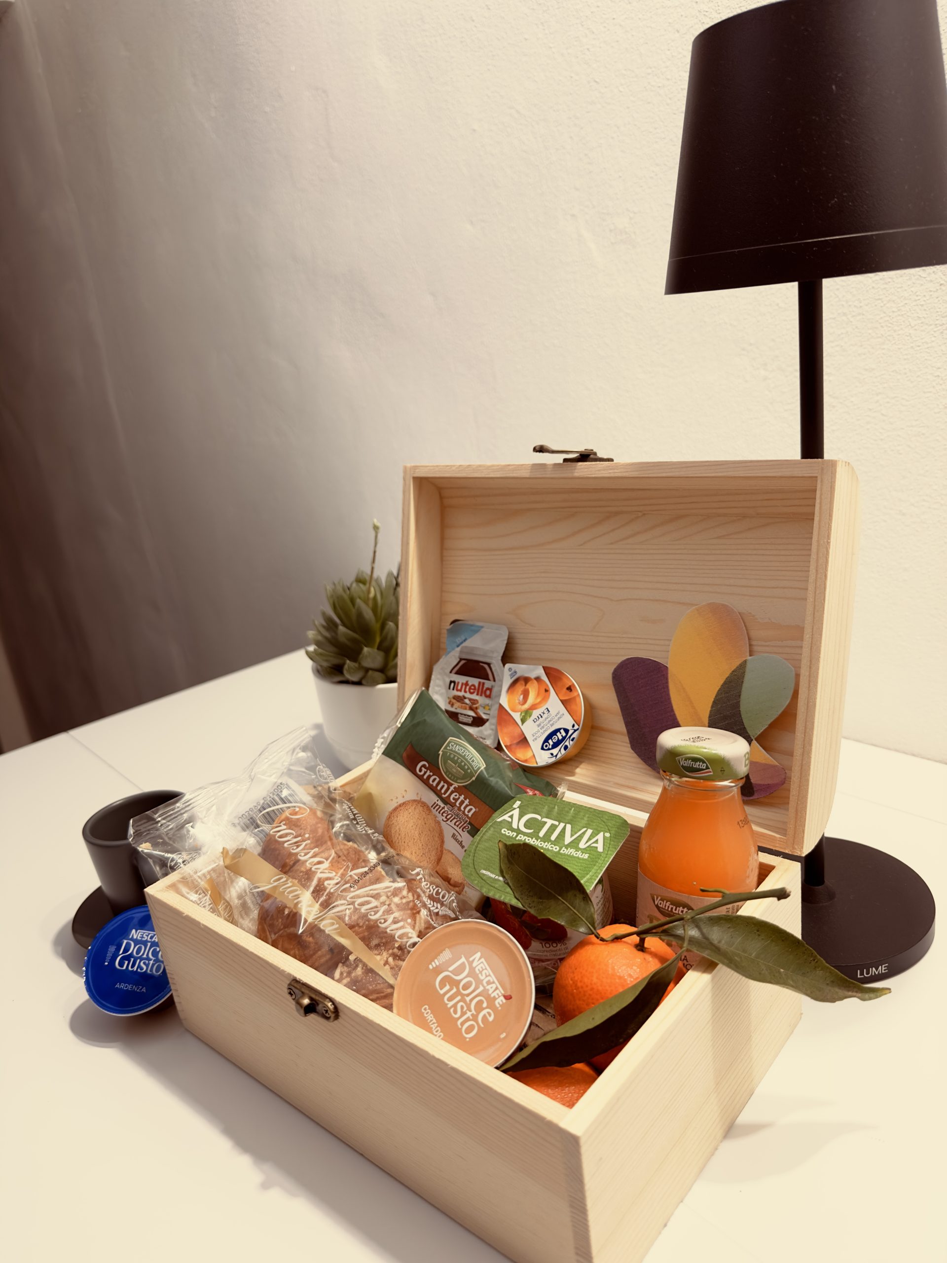 Dettaglio della box colazione con croissant, yogurt, frutta e succo di frutta nel B&B G-House a Parma.