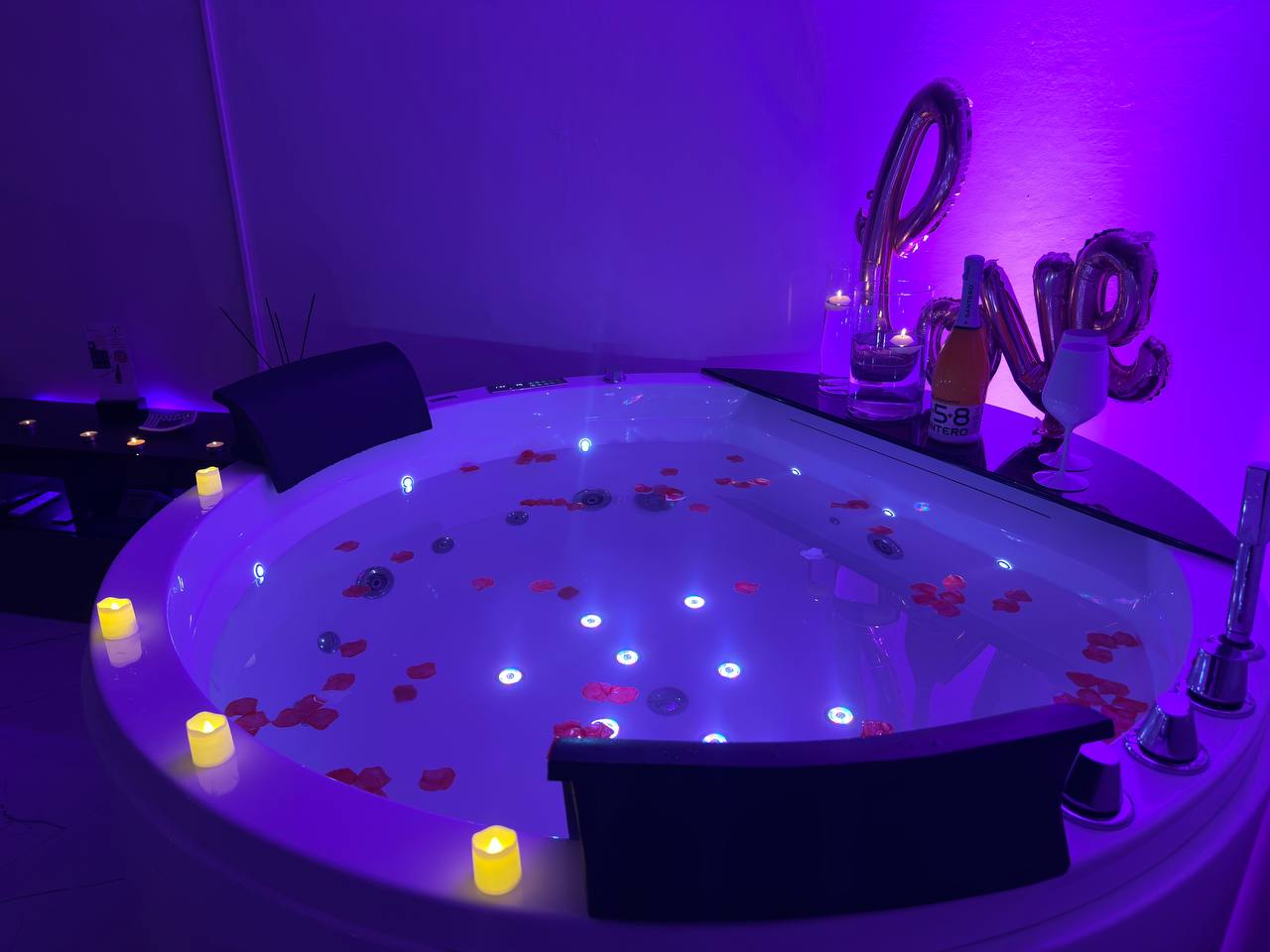 Vasca idromassaggio illuminata con petali di rosa e prosecco al G-House Bnb a Parma.